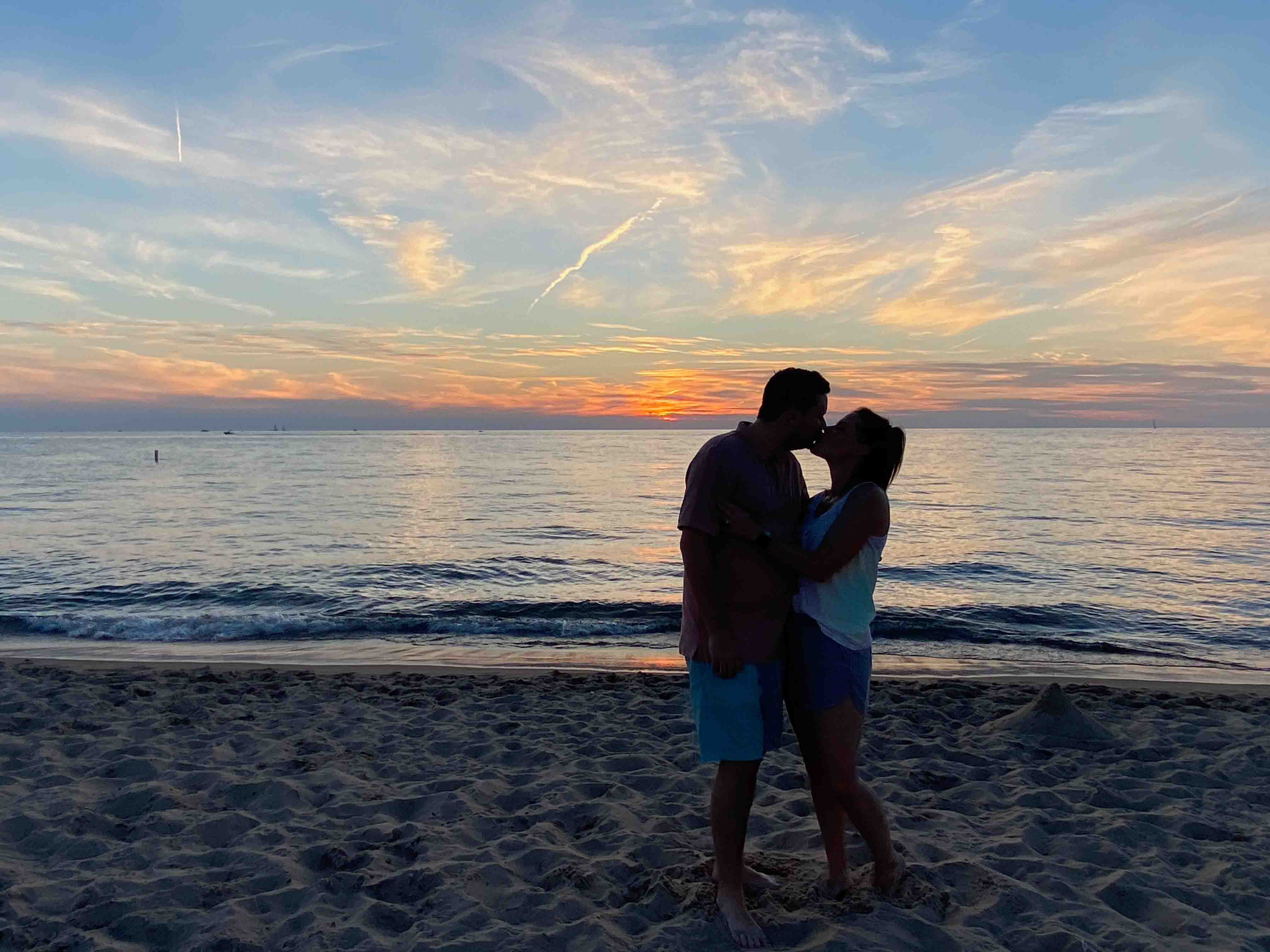 Couple kissing on the beach as the sun goes down