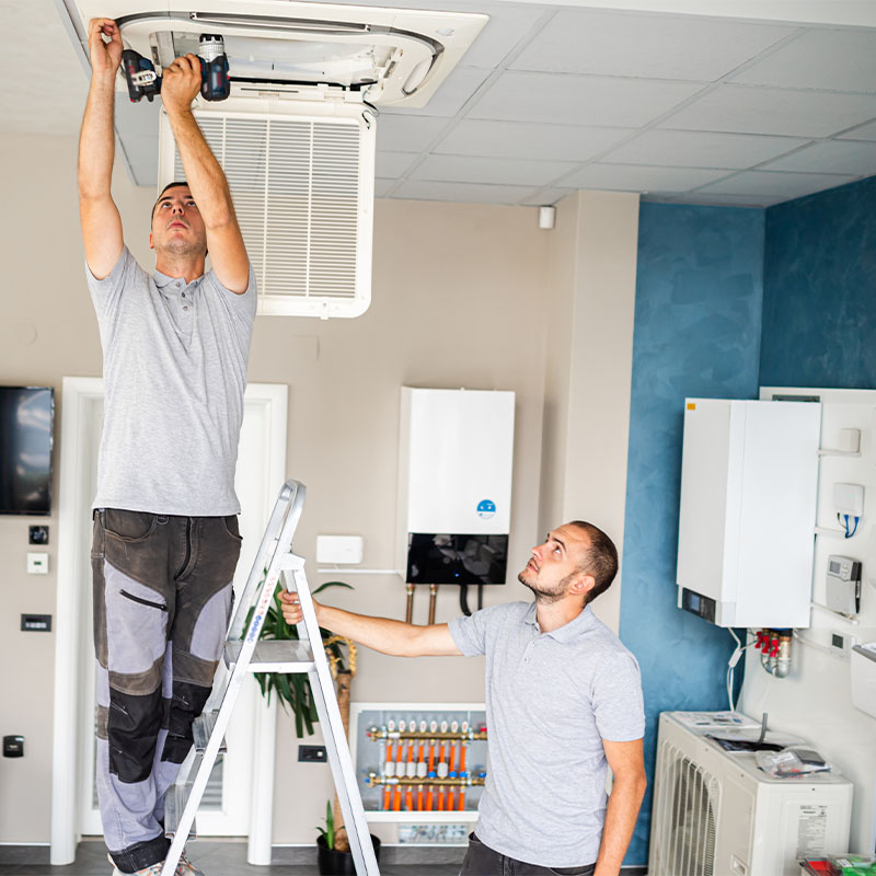 Maintenance workers fixing a air vent in a property